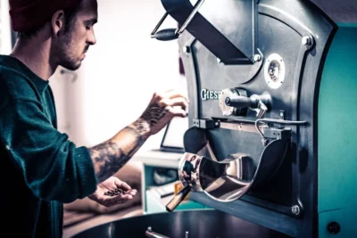 Person mit gerösteten Kaffeebohnen in der Hand vor Giessen Trommelröster